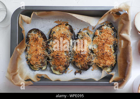 Gefüllte Auberginen gratiniert mit Fleisch und Käse von oben in eine weiße Holztisch einer rustikalen Küche. Stockfoto