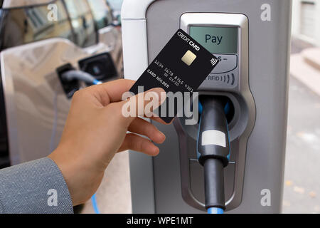 Ein Mann zahlt für das Aufladen eines Elektroautos. Stockfoto