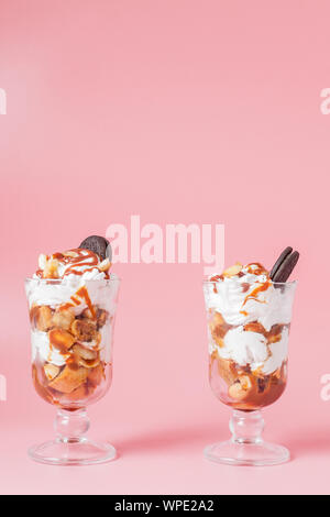Süßes Dessert im Glas mit Keks und Schlagsahne auf Rosa bsckground, selektiver Fokus und Leerzeichen Stockfoto