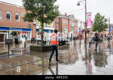 High Wycombe, Engalnd - 14. August 2019: Menschen auf der High Street im Regen. Es häufig Regen im Sommer. Stockfoto