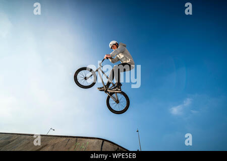Teenager, springen in die Luft mit seinem BMX-Rad in einem Skatepark. Stockfoto