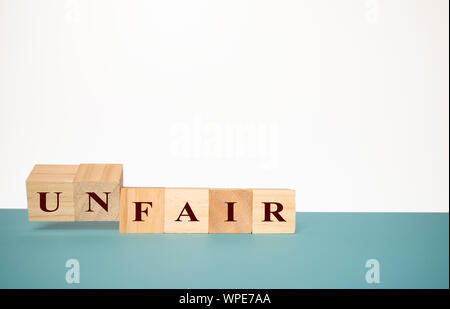 Schlagen Zwei hölzerne Würfel das Wort Unfair fair auf neutralem Hintergrund zu ändern Stockfoto