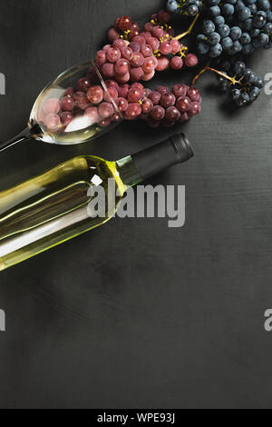 Eine Flasche, Weingläser, frischen Weintrauben auf schwarzem Hintergrund. Flach, Ansicht von oben, kopieren. Weinstube, Weingut, Weinprobe Konzept Stockfoto