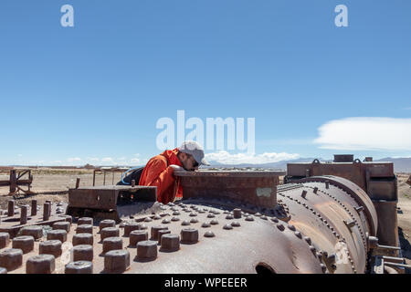 Junge kaukasier neugierig Mann an den verlassenen alten Dampflokomotive, Großer Zug Friedhof oder Dampflokomotiven Friedhof von Uyuni, Bolivien Stockfoto