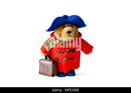 Ein Paddington Bär Plüschtier mit roten Dufflecoat, blauen Hut und Koffer, vor einem weißen Hintergrund isoliert Stockfoto