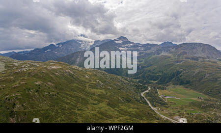 Eine hohe Alpine Mountain Valley und Mountain Road vorbei. Die Straße führt durch hohe Berge und rauhen alpinen felsiges Gelände. Storm clouds Form ov Stockfoto