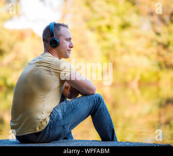Mann mit Kopfhörer Musik hören auf Herbst Hintergrund Stockfoto