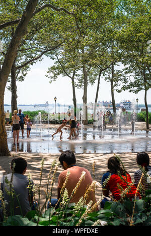 Battery Park New York, Aussicht im Sommer von Menschen genießen die Wasserstrahl Funktion im Battery Park, Manhattan, New York City, USA Stockfoto