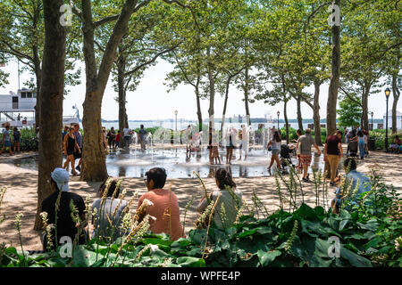 Battery Park New York, Aussicht im Sommer von Menschen genießen die Wasserstrahl Funktion im Battery Park, Manhattan, New York City, USA Stockfoto