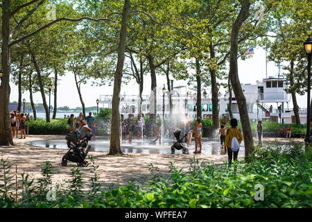 New York City Park, Ansicht im Sommer von Menschen genießen die Wasserstrahl Funktion im Battery Park, Manhattan, New York City, USA Stockfoto