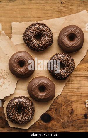 Leckere Schokolade Donuts mit Sahne und Krümel auf rustikalen Holztisch direkt von oben gesehen Stockfoto