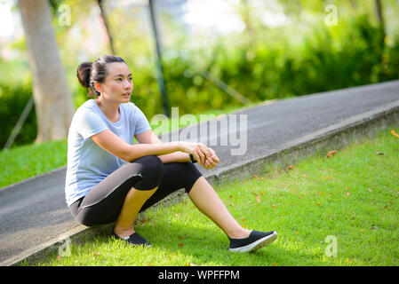 Junge Frau ausruhen nach Laufen im Park Stockfoto