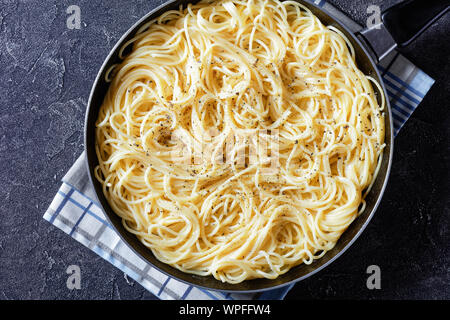 Cacio e Pepe, traditionelle italienische Teller Pasta Spaghetti mit geriebenem Pecorino vermischt und bestäubt mit frisch gemahlenem schwarzem Pfeffer in einer Pfanne, Stockfoto