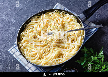 Close-up cacio e Pepe, Spaghetti mit geriebenem Käse und mit frisch gemahlenem schwarzem Pfeffer in einer Pfanne mit einer Gabel entstaubt, Ansicht von oben Stockfoto