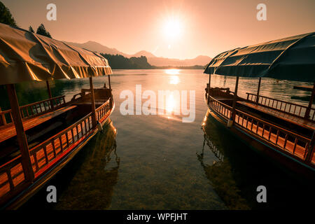 Hölzerne Boote am See Bled auf einem Pier im Sommer während Sonnenaufgang Sonnenuntergang Stockfoto