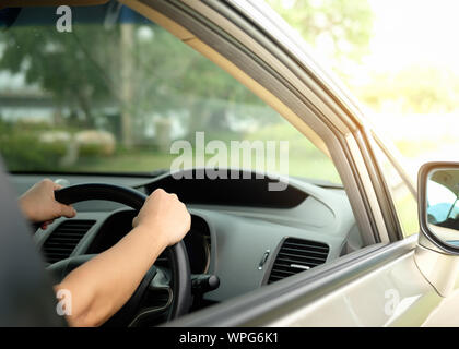 Die Hände sind Sie das Lenkrad und fährt auf einem hellen Tag. Stockfoto