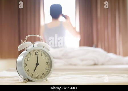 Die Wecker am Morgen, wodurch die Frau aufzuwachen und zu telefonieren. Stockfoto