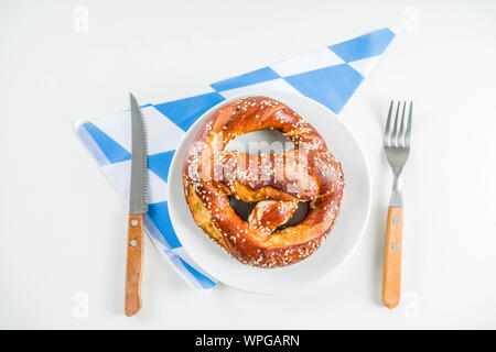 Oktoberfest festliche Besteck mit mit einem traditionellen karierten Tischdecken, Teller, Brezel, Gabel, Messer und ein Glas Bier. Hintergrund für Restor Stockfoto