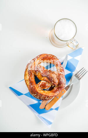 Oktoberfest festliche Besteck mit mit einem traditionellen karierten Tischdecken, Teller, Brezel, Gabel, Messer und ein Glas Bier. Hintergrund für Restor Stockfoto