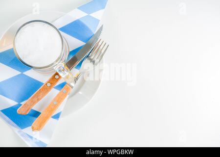 Oktoberfest festliche Besteck mit mit einem traditionellen karierten Tischdecken, Teller, Brezel, Gabel, Messer und ein Glas Bier. Hintergrund für Restor Stockfoto