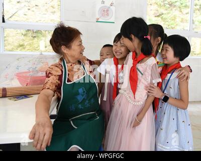 (190909) - Zhenghe, Sept. 9, 2019 (Xinhua) - Schüler sprechen mit Liang Chun'ai während einer Pause bei der Xijin sie ethnische gruppe Grundschule in Shitun Stadt, Zhenghe County im Südosten der chinesischen Provinz Fujian, Sept. 4, 2019. In der bergigen Region im Norden von Fujian, das Internat hat jetzt 165 Schüler. Unter ihnen sind 83 Studenten sind Boarder. Viele Schüler der Schule sind links hinter Kindern und von Armut betroffenen Familien kommen. Die 62-jährige principal Zhuang Guigan, die in der Bildung arbeiten seit über 40 Jahren tätig ist, wurde vor zwei Jahren nach der Pensionierung beschäftigt. Stockfoto