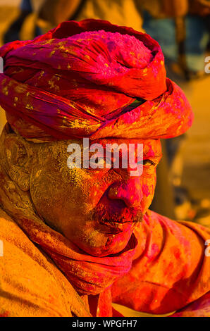 Jaisalmer, Rajasthan, Indien - 8. März, 2018: Portrait von traditionellen Mann Gesicht in den Farben bedeckt Holi Festival Konzept, Mann mit roten Turban Stockfoto