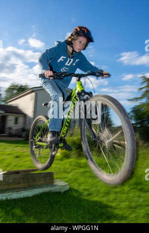 Teenager Sprüngen auf dem Fahrrad im Garten auf der Rückseite Stockfoto