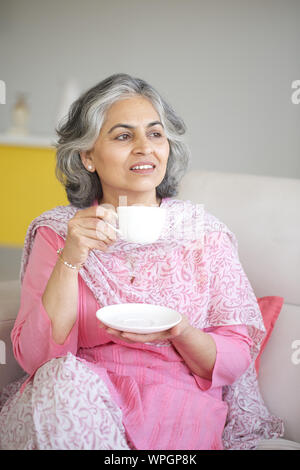 Ältere Frau trinkt Tee und Tag träumen Stockfoto
