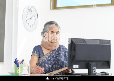 Geschäftsfrau trägt eine Nackenstütze und arbeitet in einem Büro Stockfoto