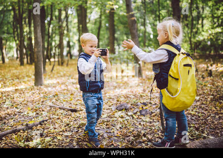 Kinder im Vorschulalter kaukasischen Bruder und Schwester Bilder von einander auf Handy Kamera in Forest Park Herbst. Thema der Hobby- und Aktiv Stockfoto