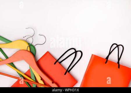 Zwei orangefarbenen Papier Einkaufstüten mit bunten Kleiderbügel mit weißem Hintergrund. Herbst Sale Konzept. Flach kopieren Raum Stockfoto