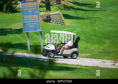 Murcia, Spanien, 25. August 2019: Sportler, ein Golf Cart in einem Spanisch-Kurs. Zwei Männer spielen Golf spielt im Sommer. Grünes Gras, spielt. Stockfoto