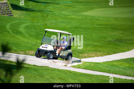 Murcia, Spanien, 25. August 2019: Sportler, ein Golf Cart in einem Spanisch-Kurs. Zwei Männer spielen Golf spielt im Sommer. Grünes Gras, spielt. Stockfoto