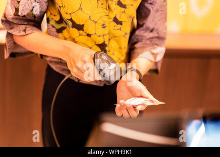 Frau an der Kasse Barcode von einem Etikett scannen. Stockfoto