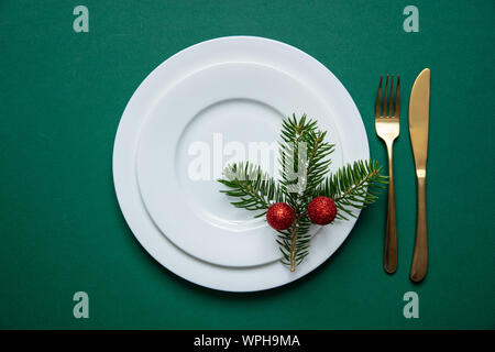 Neues Jahr, Weihnachten Abendessen Tabelle einstellen. Tannenbaum, Zweige auf weißem Geschirr isoliert, grüne Farbe Hintergrund, Ansicht von oben Stockfoto