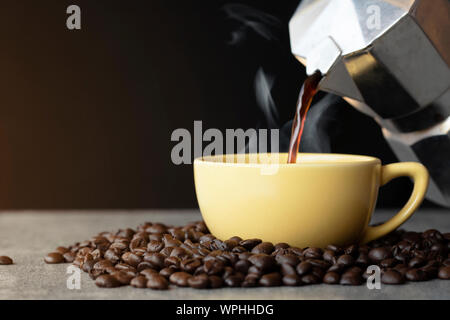 Kaffee Eingießen in die Tasse mit Kaffee Bohne auf schwarzem Hintergrund Stockfoto