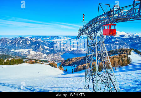 Der Blick von der Spitze des Zwolferhorn Berg auf die Seilbahn Turm, bunt vintage Kabinen und den Wolfgangsee Tal, umgeben von Alpen, St Stockfoto