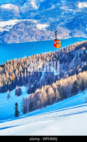 Die Vintage red Gondel der Zwolferhorn Air Lift, Reiten über die schneebedeckten Berge slpe mit einem Blick auf den Wolfgangsee auf Hintergrund, St Gilden, Salzkam Stockfoto