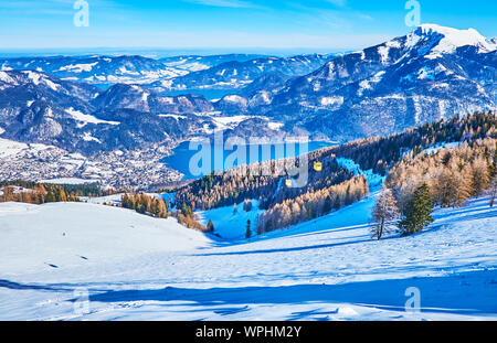 Zwolferhorn mount ist schöner Ort rocky Alpen, hellen blauen Wolfgangsee und retro Kabinen der Seilbahn zu beobachten, laufen entlang der schneebedeckten Hang, wi Stockfoto