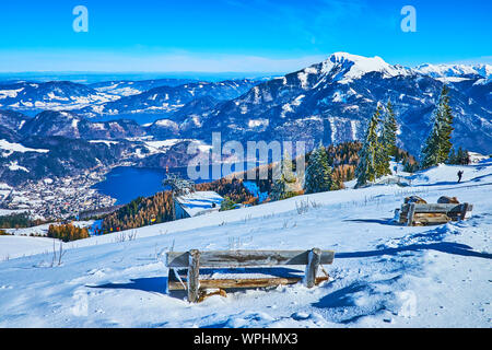 Die alten hölzernen Bänke sind in Tiefen schneewehen am Hang des Zwolferhorn versteckte Montage, mit Blick auf die Salzkammergut Landschaft, Wolfgangsee und Mondsee lak Stockfoto