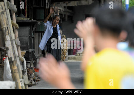 (190909) - CHANGSHA, Sept. 9, 2019 (Xinhua) - Tang Shangjun (L) Wellen Abschied von Studierenden außerhalb seines Hauses in Wuhan Dorf Anhua County in Yiyang City, Chinas Provinz Hunan, Sept. 8, 2019. Ein Holzhaus steht allein in den tiefen Bergen durch einen lebhaften grünen Decke von Bäumen bedeckt, nicht nur als Wohnung, sondern auch als ein Klassenzimmer, wo Tang Shangjun Nachhilfe Studenten Seit mehr als 20 Jahren. Tang, einem 92-jährigen ländlichen Lehrer, nachhilfe begonnen, die Kinder durch ihre Eltern mit Migrationshintergrund kostenlos Links in Wuhan Dorf im Jahre 1997, 10 Jahre nach seiner Pensionierung von Teachin Stockfoto