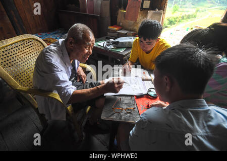 (190909) - CHANGSHA, Sept. 9, 2019 (Xinhua) - Tang Shangjun Tutoren Schüler an seinem Haus in Wuhan Dorf Anhua County in Yiyang City, Central China Provinz Hunan, Sept. 8, 2019. Ein Holzhaus steht allein in den tiefen Bergen durch einen lebhaften grünen Decke von Bäumen bedeckt, nicht nur als Wohnung, sondern auch als ein Klassenzimmer, wo Tang Shangjun Nachhilfe Studenten Seit mehr als 20 Jahren. Tang, einem 92-jährigen ländlichen Lehrer, nachhilfe begonnen, die Kinder durch ihre Eltern mit Migrationshintergrund kostenlos Links in Wuhan Dorf im Jahre 1997, 10 Jahre nachdem er vom Unterrichten in Anhua County zurückgezogen. Stockfoto