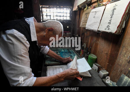 (190909) - CHANGSHA, Sept. 9, 2019 (Xinhua) - Tang Shangjun Art Lehre Skripte zu Hause in Wuhan Dorf Anhua County in Yiyang City, Chinas Provinz Hunan, Sept. 8, 2019. Ein Holzhaus steht allein in den tiefen Bergen durch einen lebhaften grünen Decke von Bäumen bedeckt, nicht nur als Wohnung, sondern auch als ein Klassenzimmer, wo Tang Shangjun Nachhilfe Studenten Seit mehr als 20 Jahren. Tang, einem 92-jährigen ländlichen Lehrer, nachhilfe begonnen, die Kinder durch ihre Eltern mit Migrationshintergrund kostenlos Links in Wuhan Dorf im Jahre 1997, 10 Jahre nachdem er vom Unterrichten in Anhua zählen im Ruhestand Stockfoto