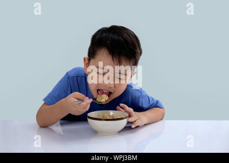 Die Asian Boy ist das Essen lecker Reis und hat ein sehr glückliches Gesicht. Stockfoto