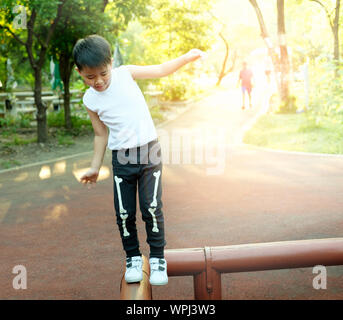 Asian Boy Balancieren auf Holz im Park. Stockfoto