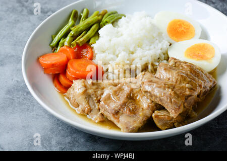 Gebackene Schweinerippchen mit Reis, gekochtes Ei und Gemüse Stockfoto