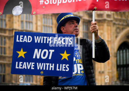 London, Großbritannien. 9 Sep, 2019. Ein Demonstrator steht außerhalb der Häuser des Parlaments Plakate in London, Großbritannien Holding, an Sept. 9, 2019. Das britische Parlament wird am am Montag Nacht prorogued werden bis Okt. 14, Downing Street bestätigt. Die Bewegung kam, nachdem Premierminister Boris Johnson die Königin forderte eine Aussetzung, von einem Datum in dieser Woche bis zum 14. Oktober. Credit: Alberto Pezzali/Xinhua Stockfoto