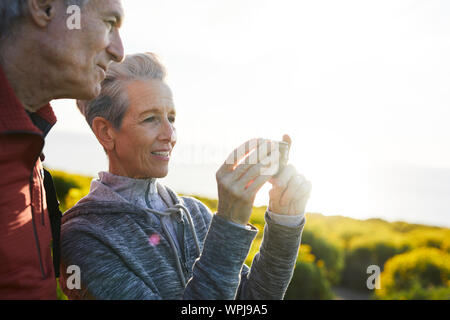 Lächelnd Mann durch ältere Frau Fotografieren durch Smart Phone, während gegen den klaren Himmel stehen Stockfoto