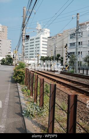 MATSUYAMA, Japan - 02.August 2019: ein vertikaler braun Schienen durch Gebäude in einer Stadt unter einem blauen Himmel umgeben Stockfoto