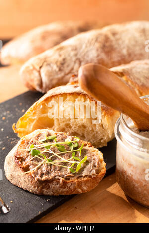 Essen Konzept Französisch beefs Rillettes verteilen sich auf hausgemachte knusprige Artisan ciabatta Brot mit Flachs microgreen für Frühstück oder Imbiss Stockfoto